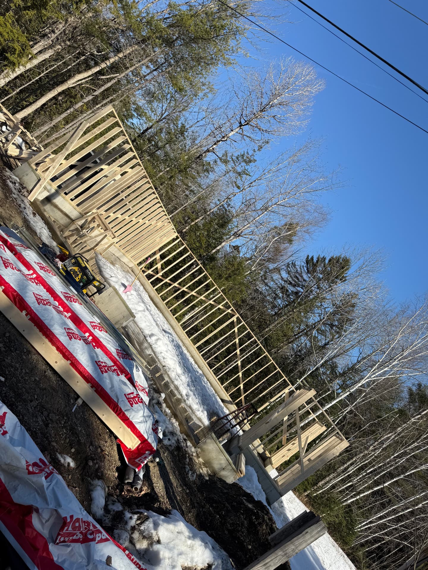 Deck and porch framing over a new foundation on a wooded Maine lot