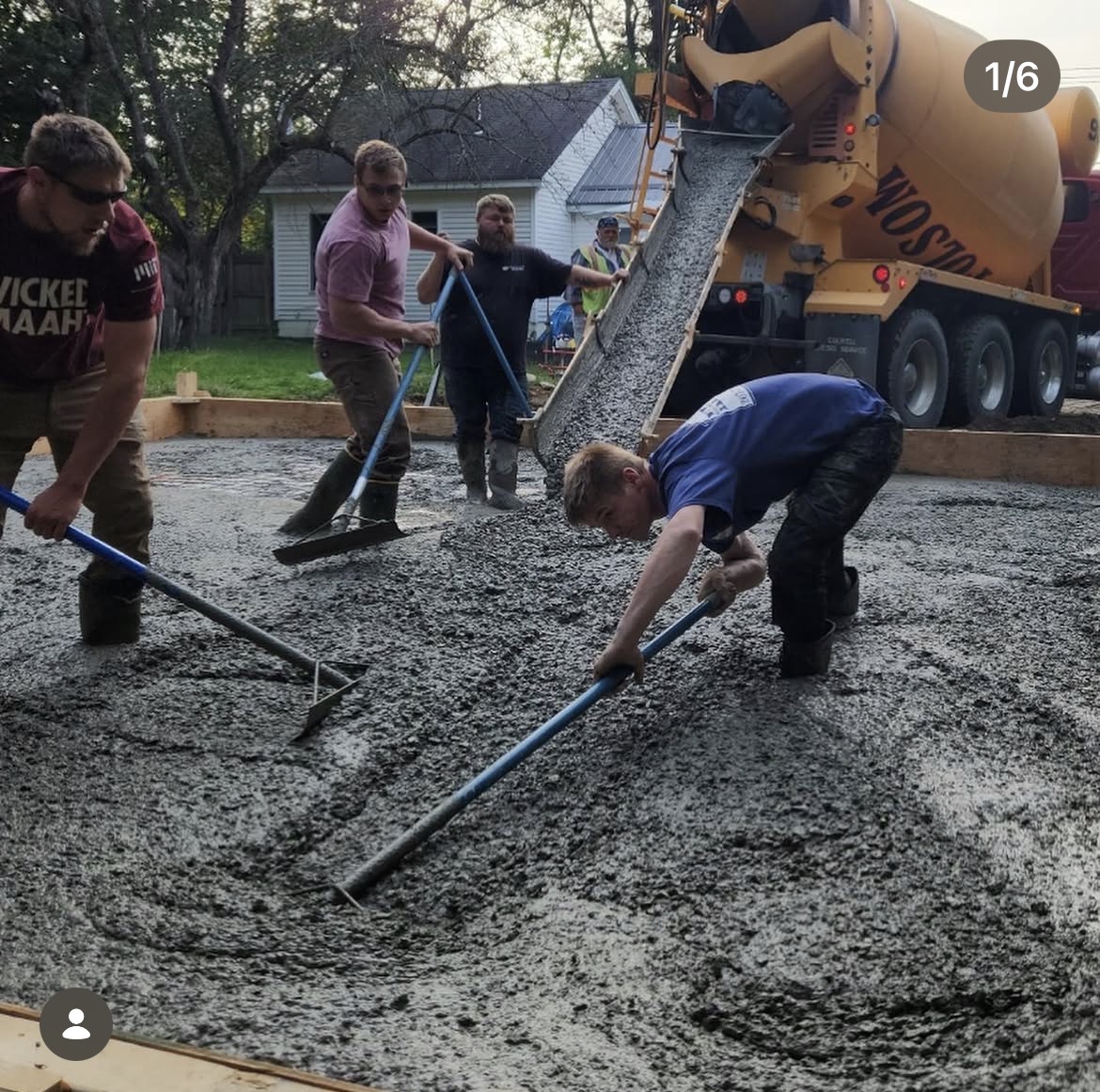 Crew raking and screeding wet concrete as a ready-mix truck pours a new slab in Maine