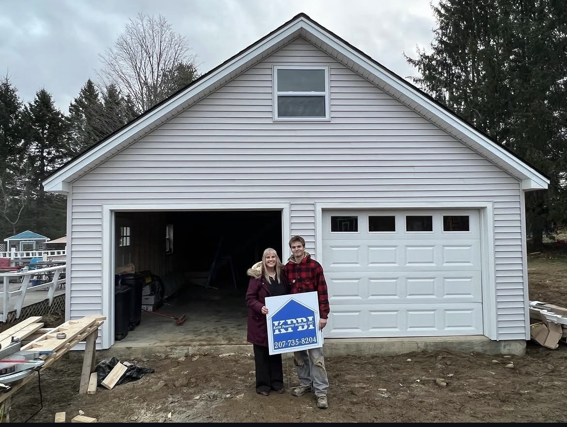 Happy homeowners with the KPBI sign in front of their completed attached garage