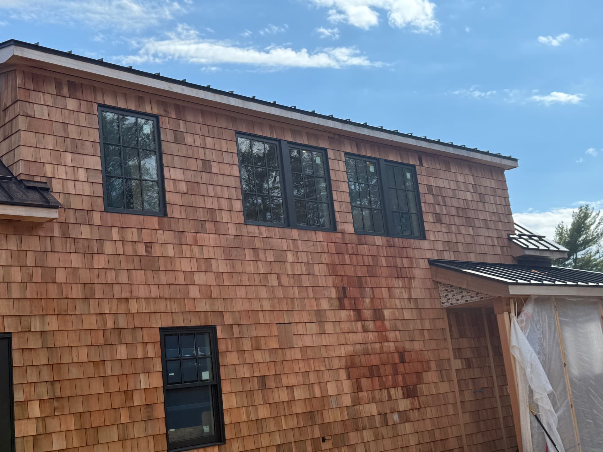 Second story cedar shingle siding with black grid windows on a new Maine home
