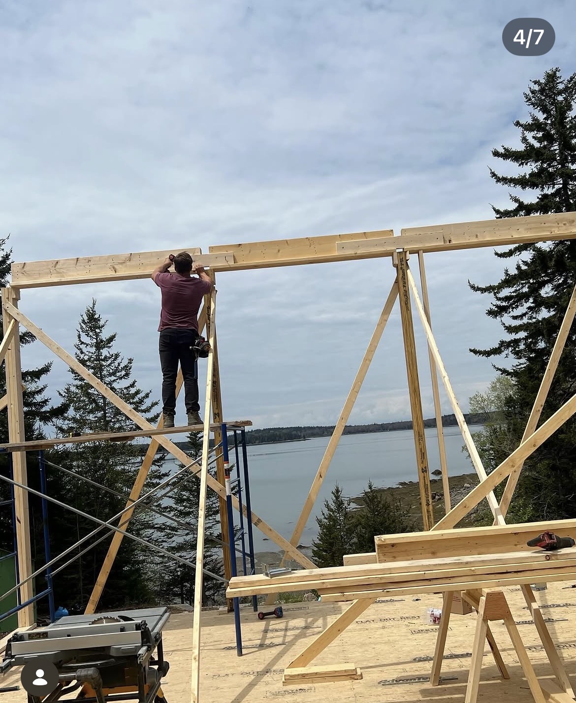 Carpenter setting a header on a framed wall overlooking the water