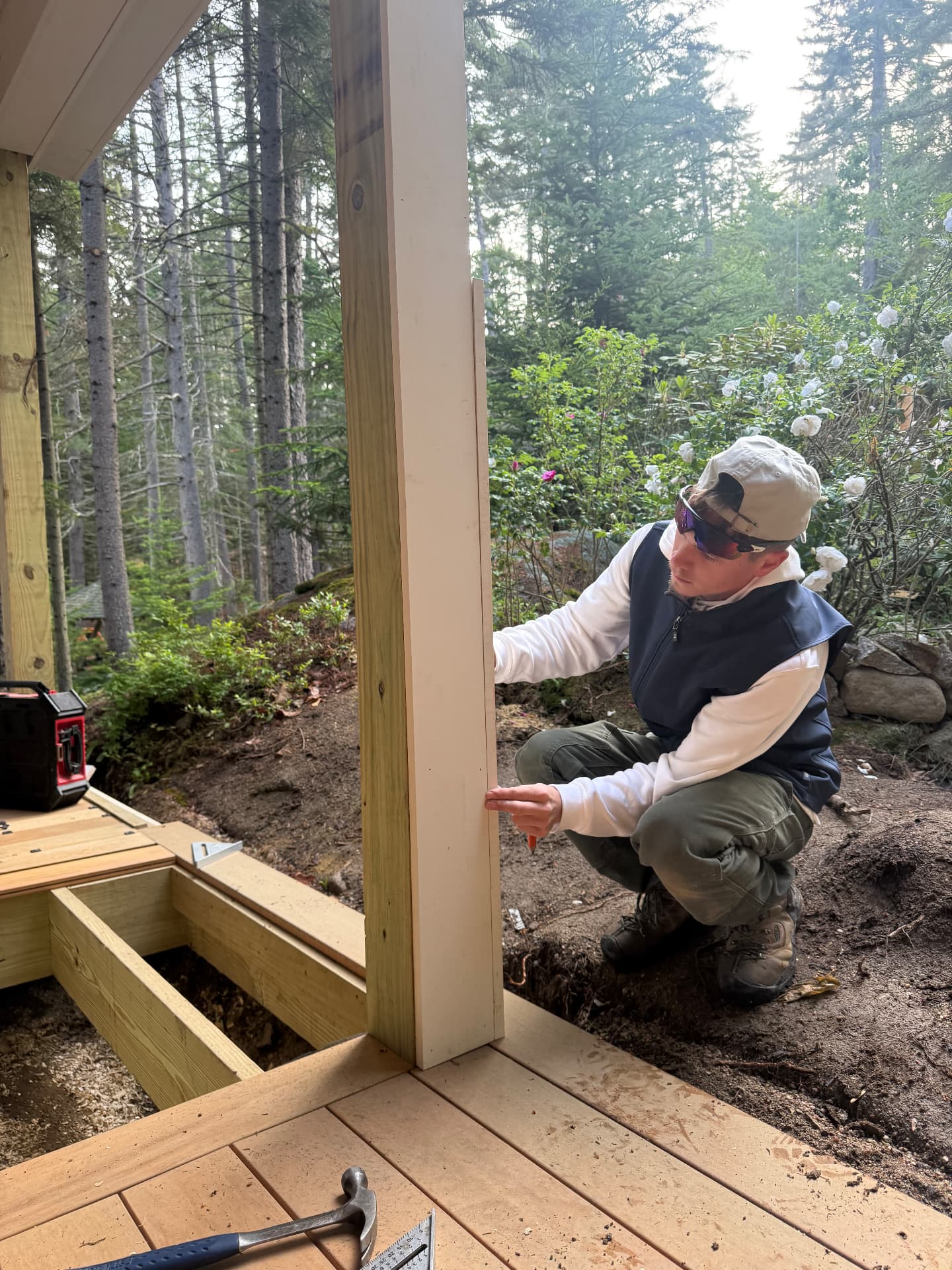 Keith Pomeroy setting a porch post during a Maine deck and porch build