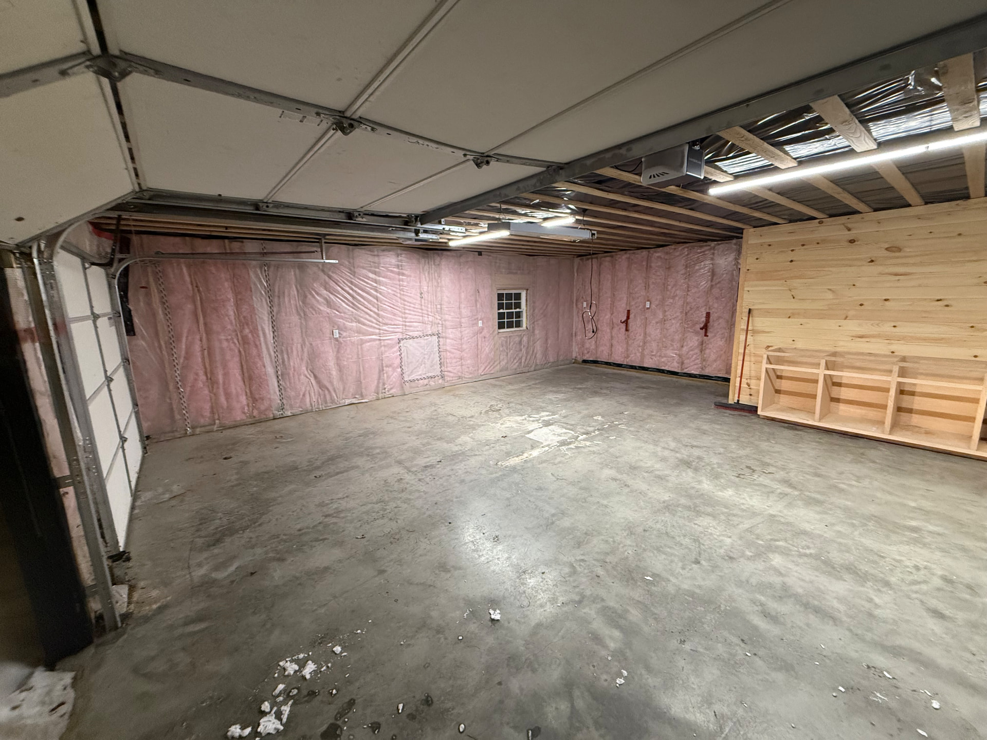 Insulated garage interior finished with pine wall paneling and built-in shelving