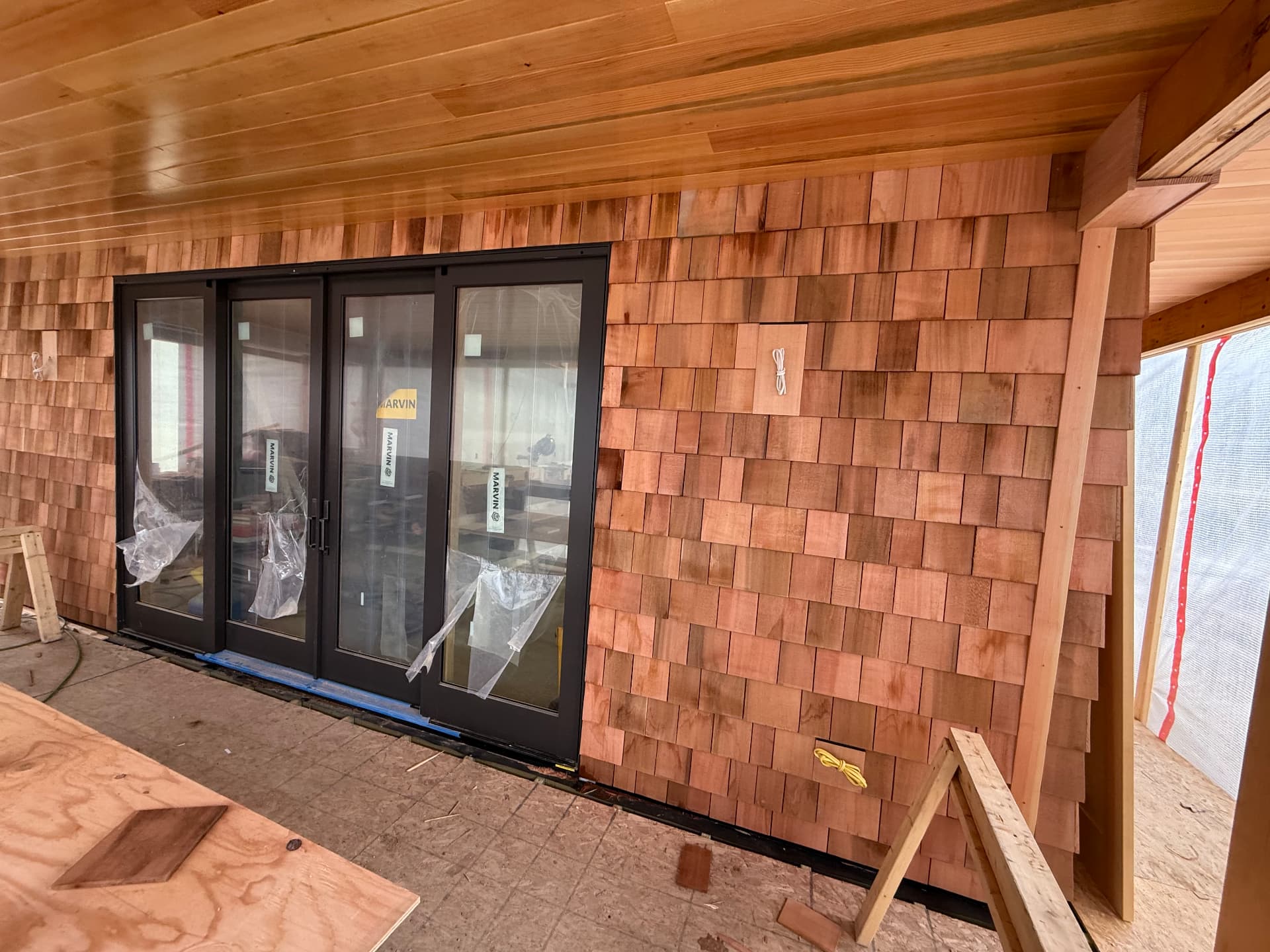 Marvin sliding patio doors set in fresh cedar shingle siding under a cedar porch ceiling