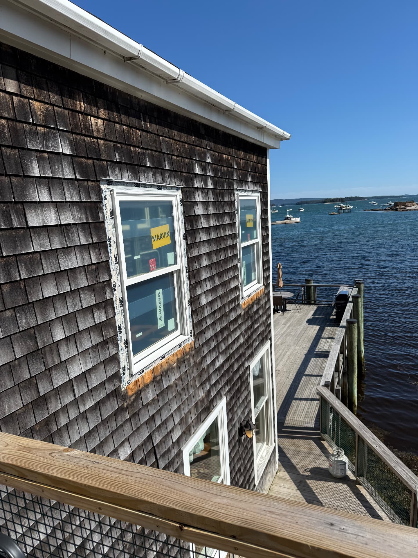 New Marvin windows installed on a shingled home overlooking a Maine harbor