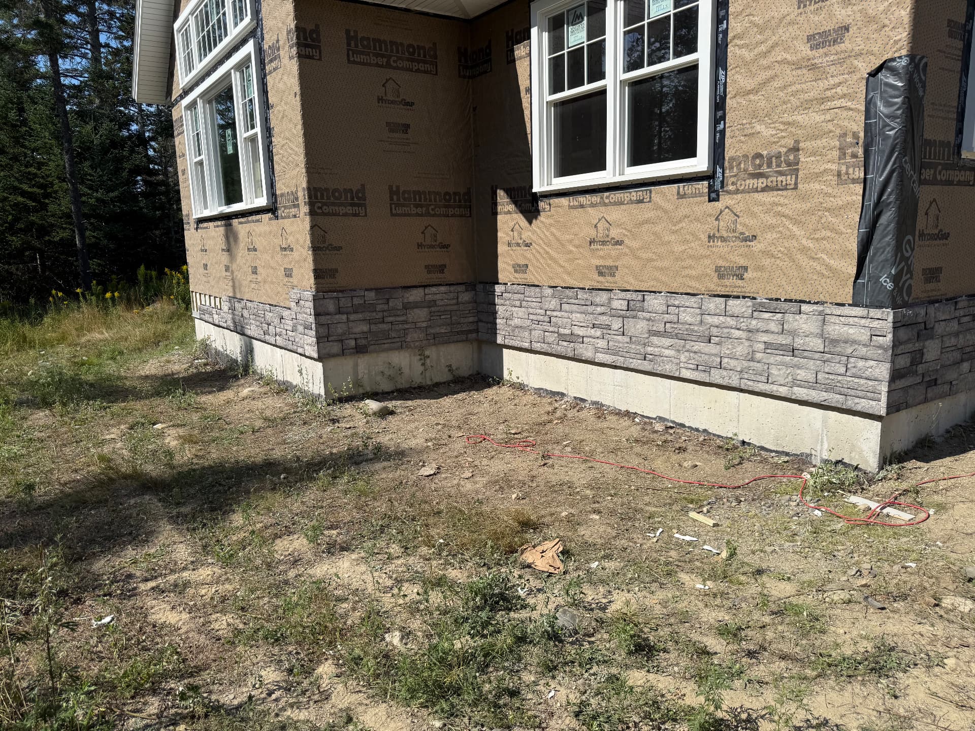 Corner view of stone veneer and drainable housewrap on a new home under construction