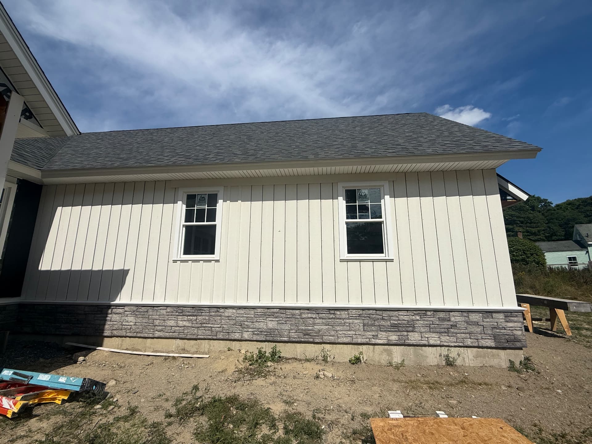 Completed ranch home with board-and-batten siding and stone veneer skirting