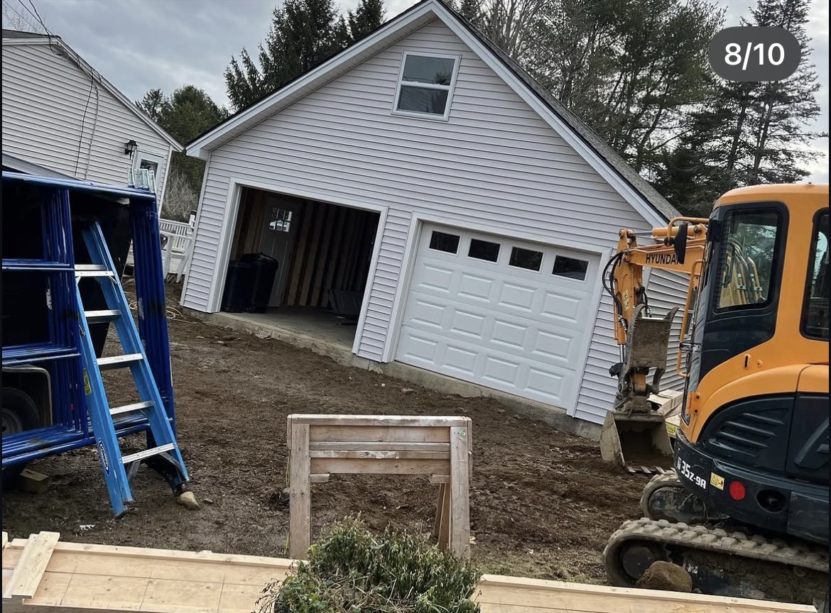 Finished attached garage with white vinyl siding and a new overhead door