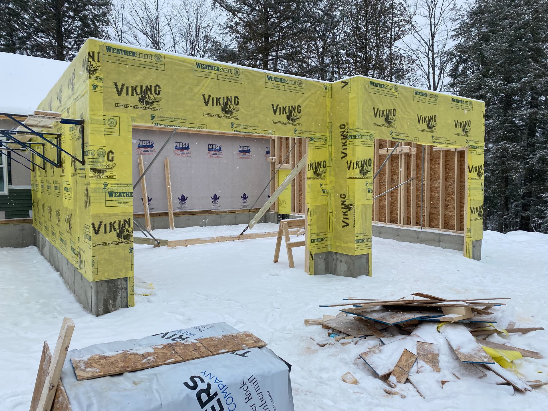 Home addition wrapped in weather barrier during a Maine snowstorm