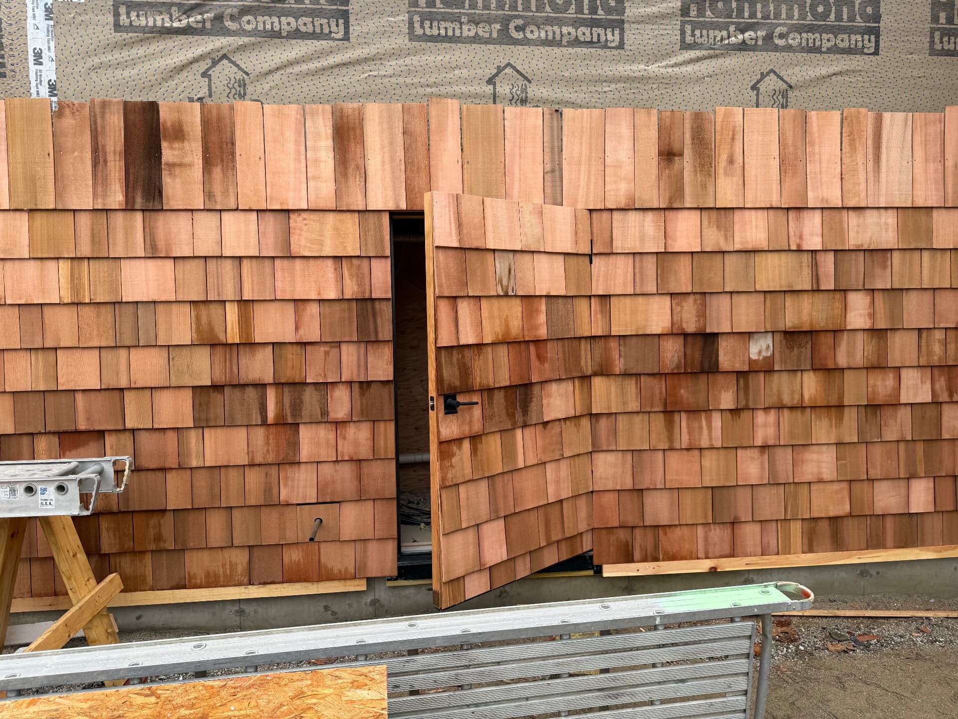 Cedar shingle siding in progress around a custom cedar-clad exterior door