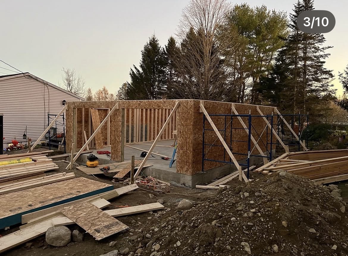 Garage walls sheathed with OSB and braced with scaffolding at dusk