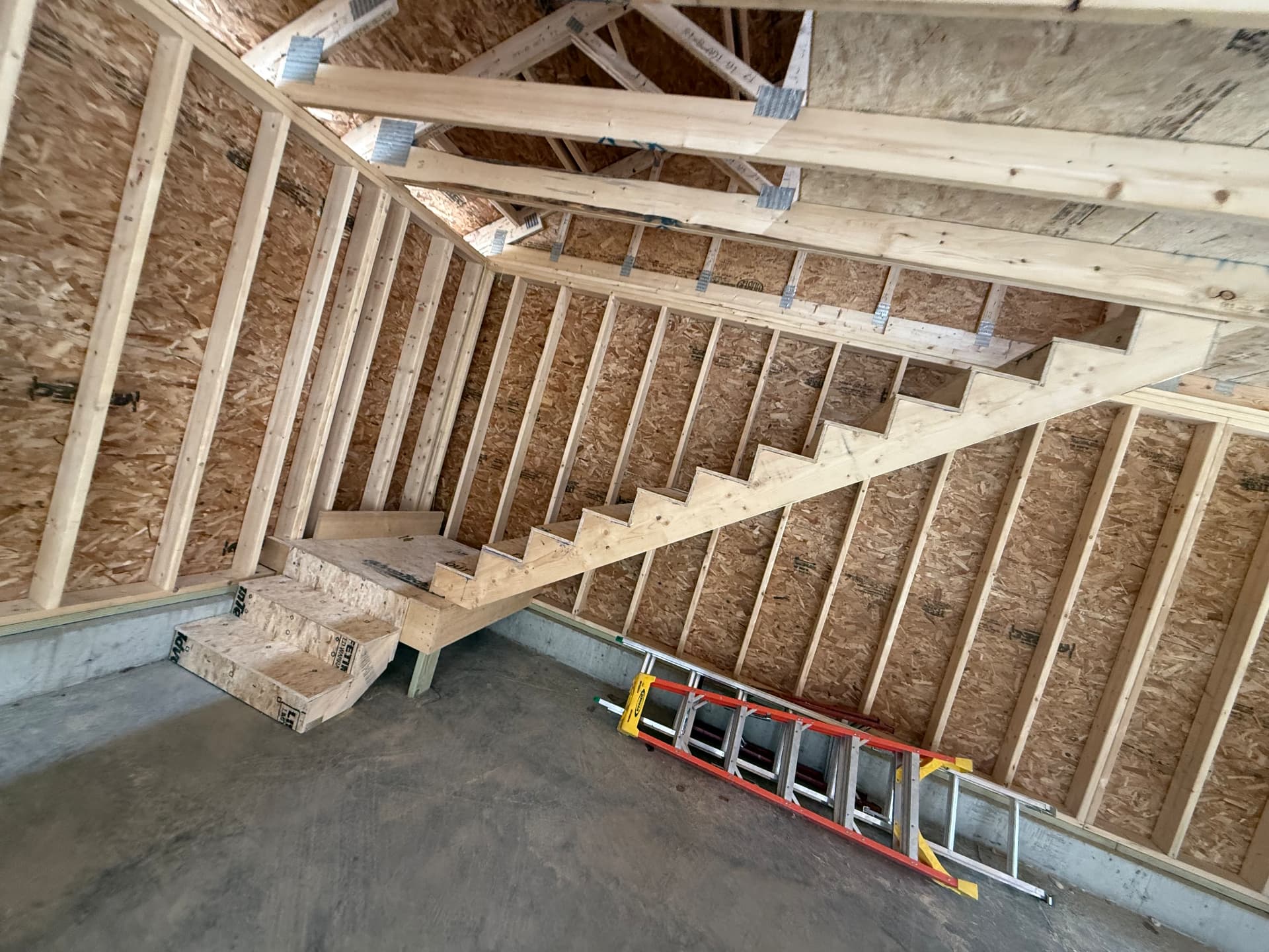 Framed staircase to a garage loft with truss ceiling above