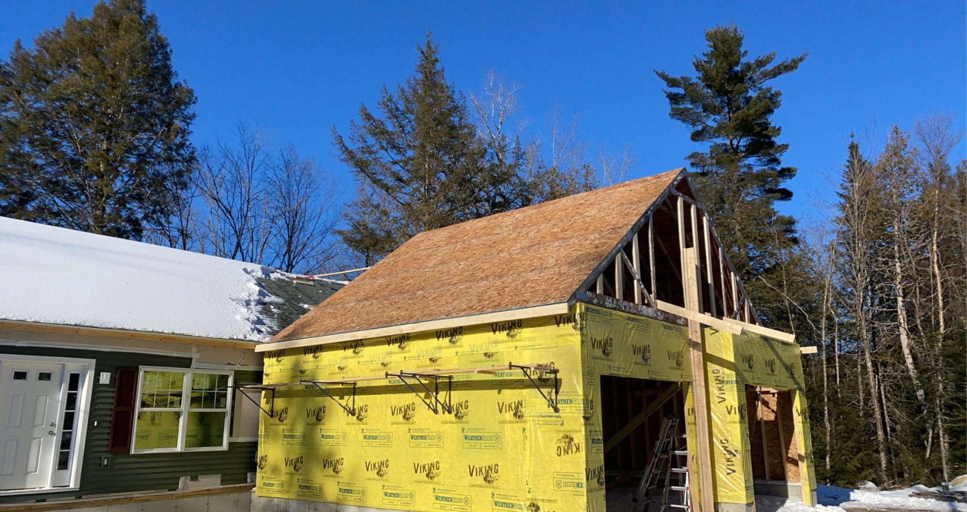 New attached garage addition with roof sheathing and house wrap in winter