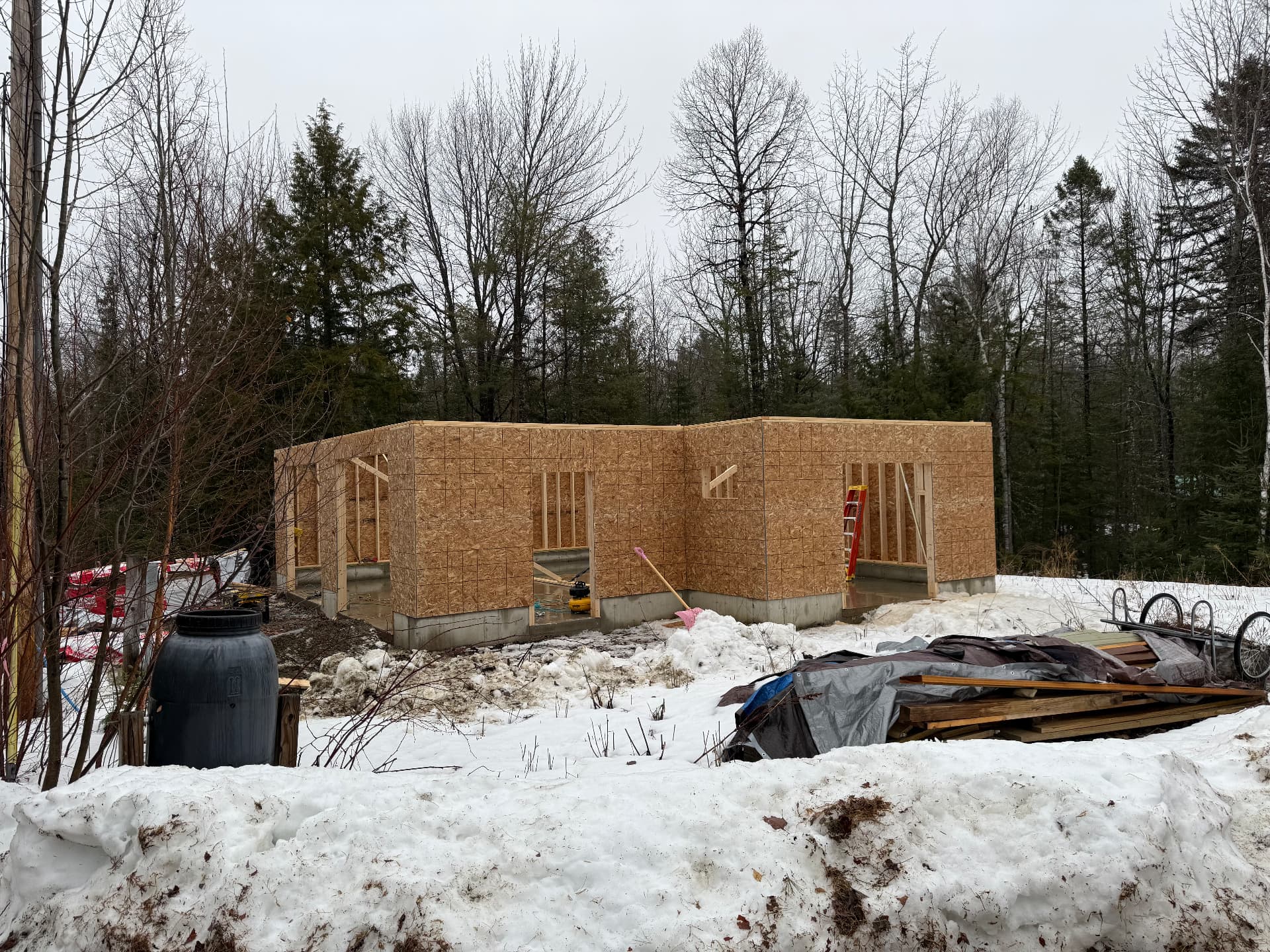 New garage shell sheathed on a poured foundation during a Maine winter
