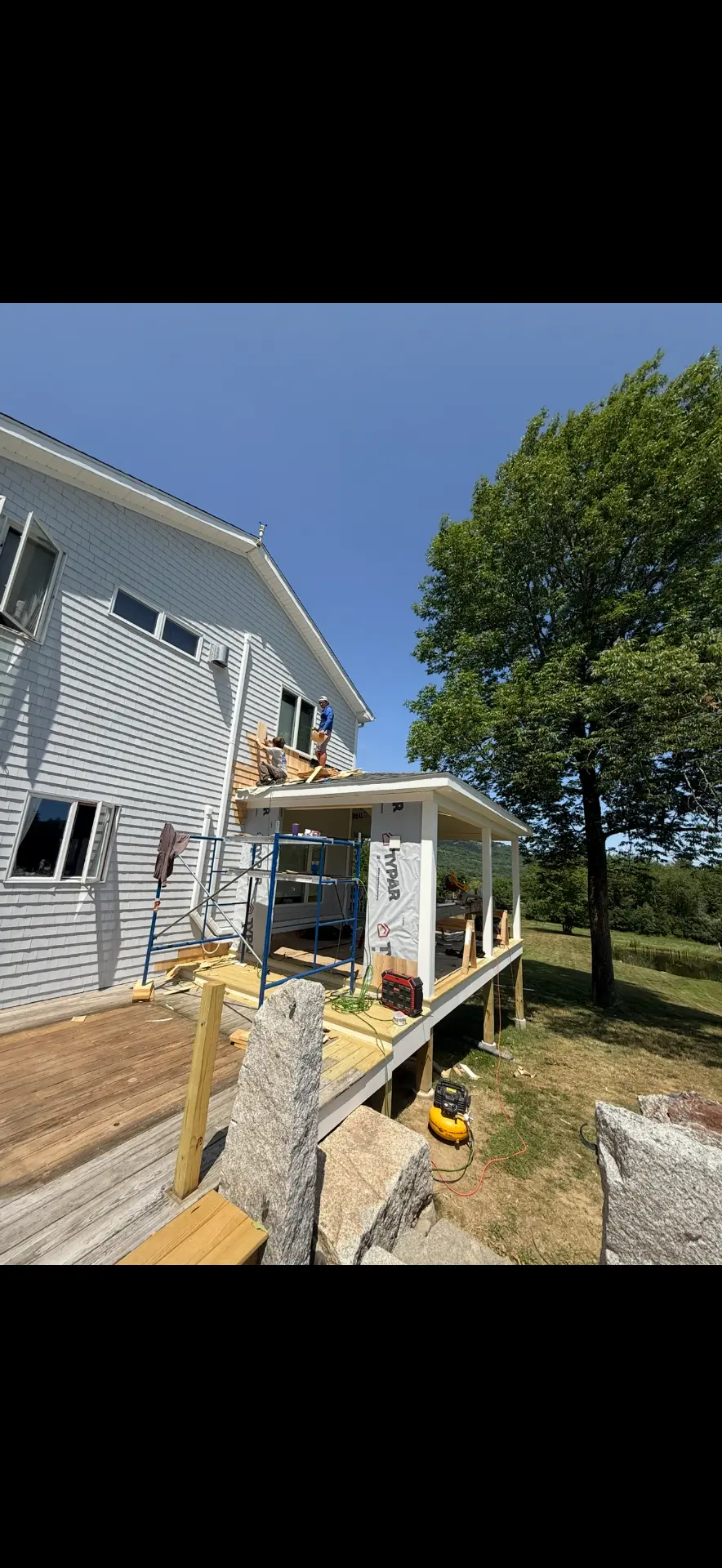 Scaffolding set up for a new screened porch addition on a shingled Maine camp