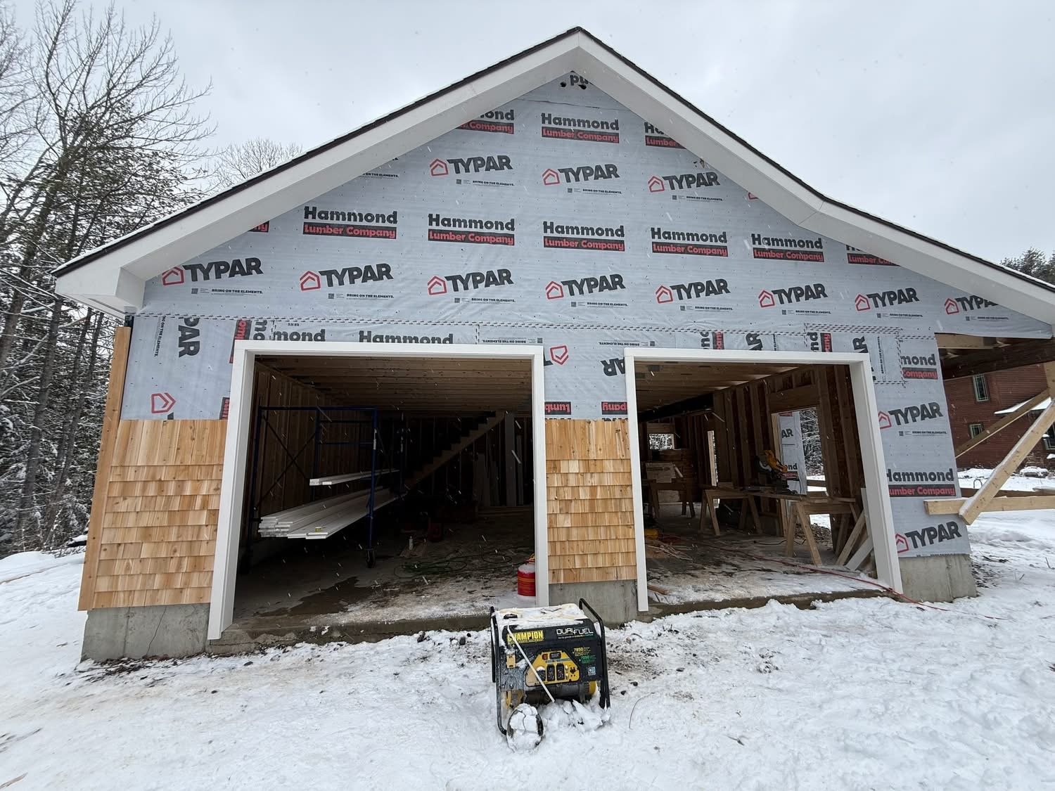 New two-bay detached garage with cedar shingle siding in winter